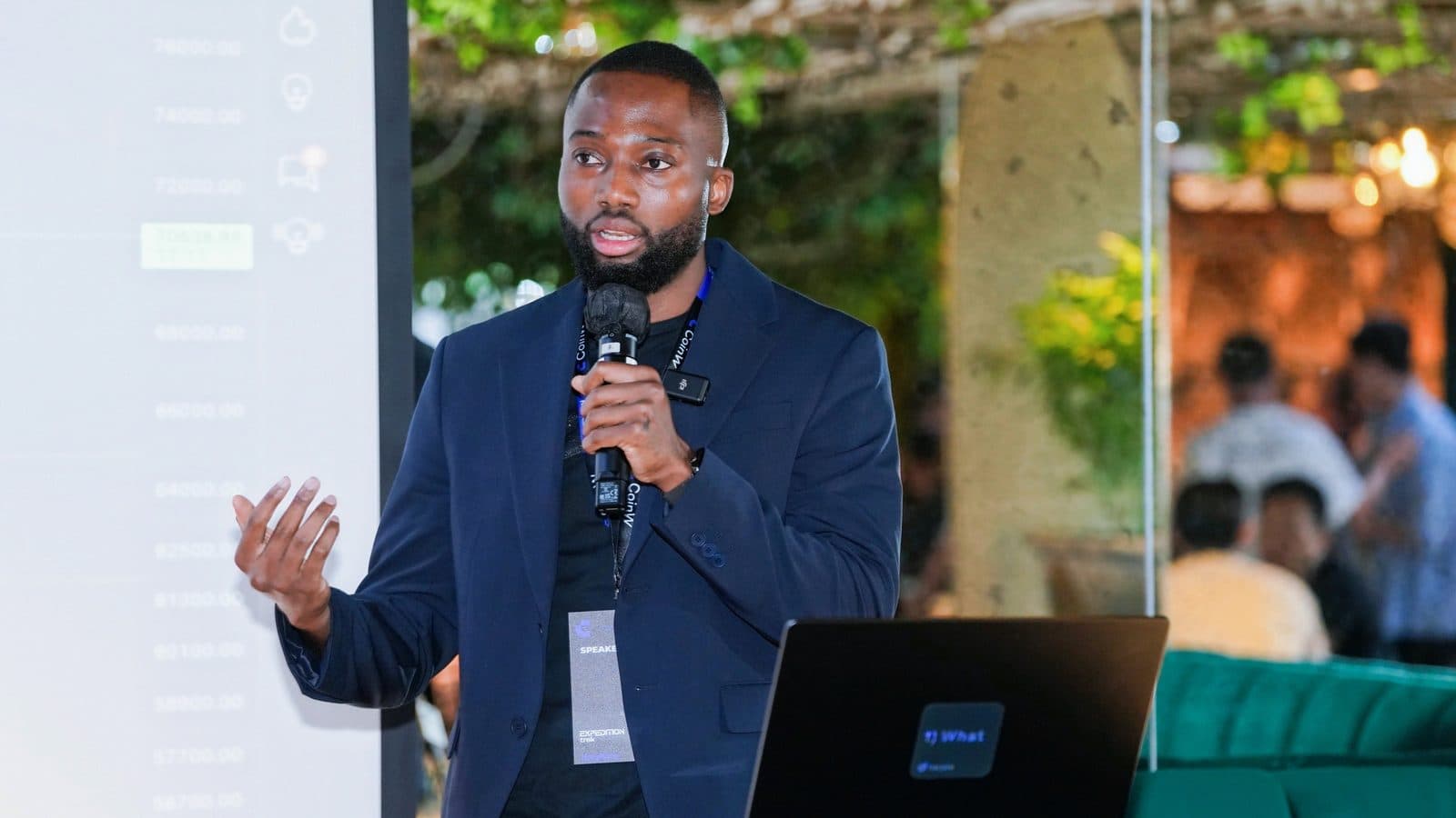 Grey Jabesi presenting with a microphone and laptop, used for an article about YouTube, AI, and distribution systems.